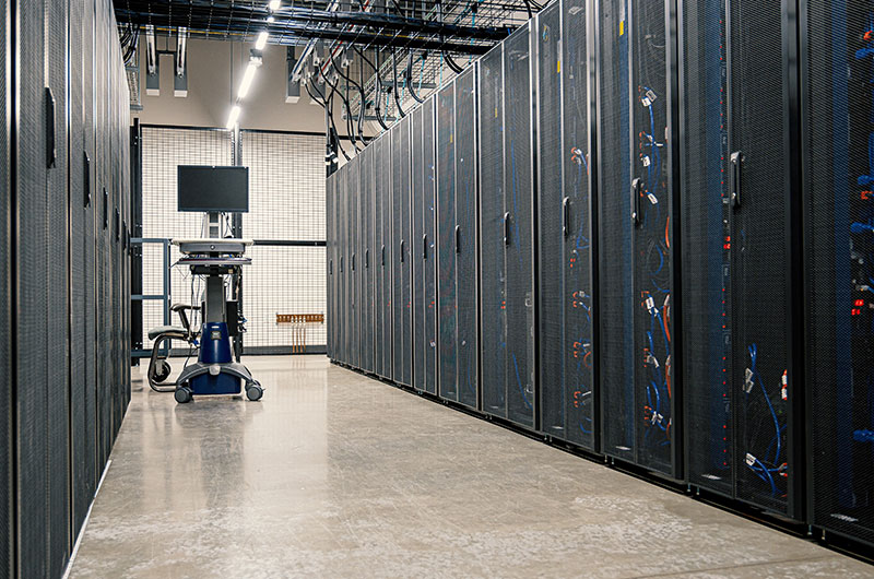 A Data Center hallway with walls of server racks and a computer cart